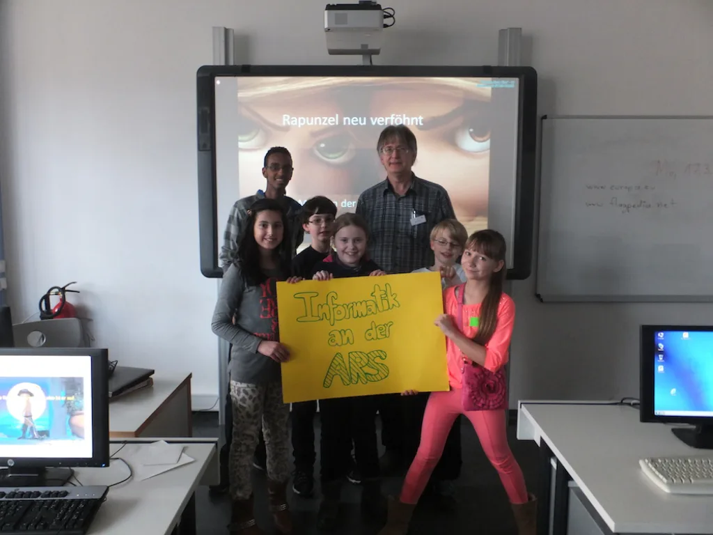 Gruppe steht vor einer Projektion, zwei halten ein Schild.